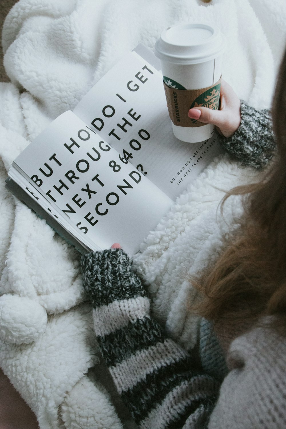 femme assise sur le lit tout en tenant une tasse Starbucks