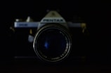 A vintage camera with a prominent lens takes center focus against a dark background. The branding and text around the lens are visible, adding a nostalgic touch.