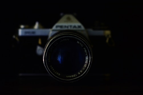 A vintage camera with a prominent lens takes center focus against a dark background. The branding and text around the lens are visible, adding a nostalgic touch.