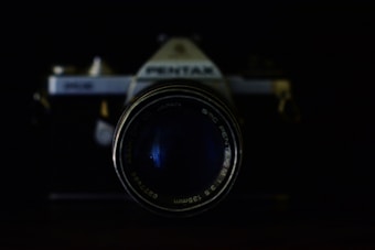 A vintage camera with a prominent lens takes center focus against a dark background. The branding and text around the lens are visible, adding a nostalgic touch.