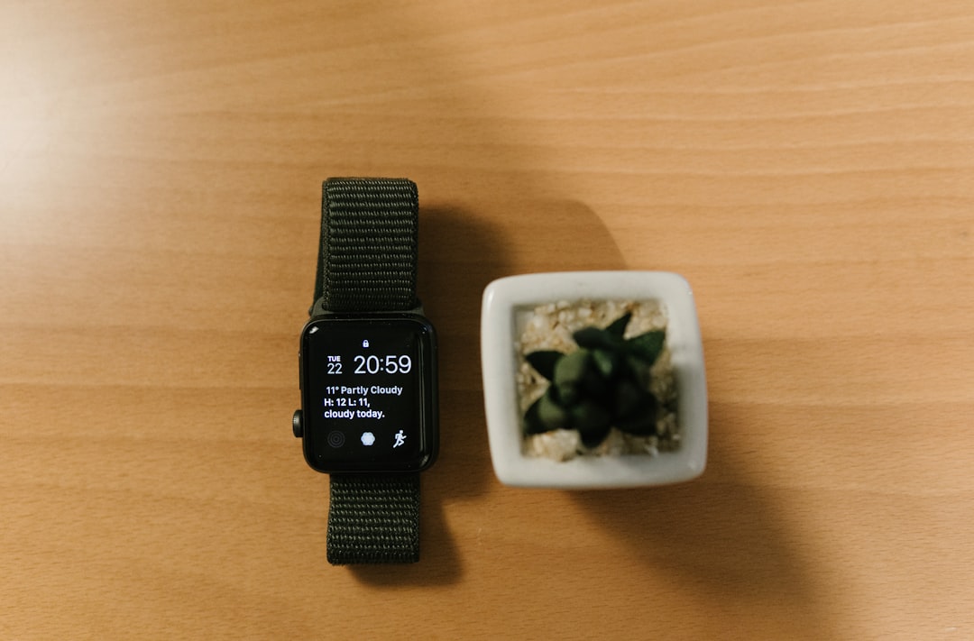 space gray Aluminum Case Apple Watch with black strap beside green succulent plant on brown wooden surface