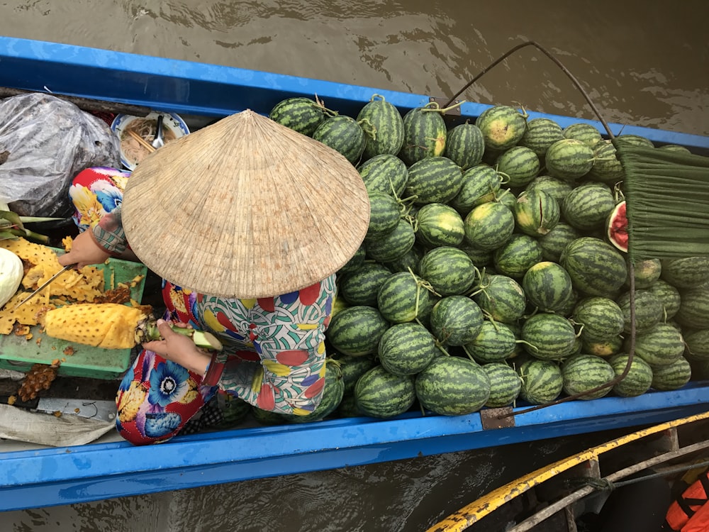 person wearing brown hat slicing pineappling