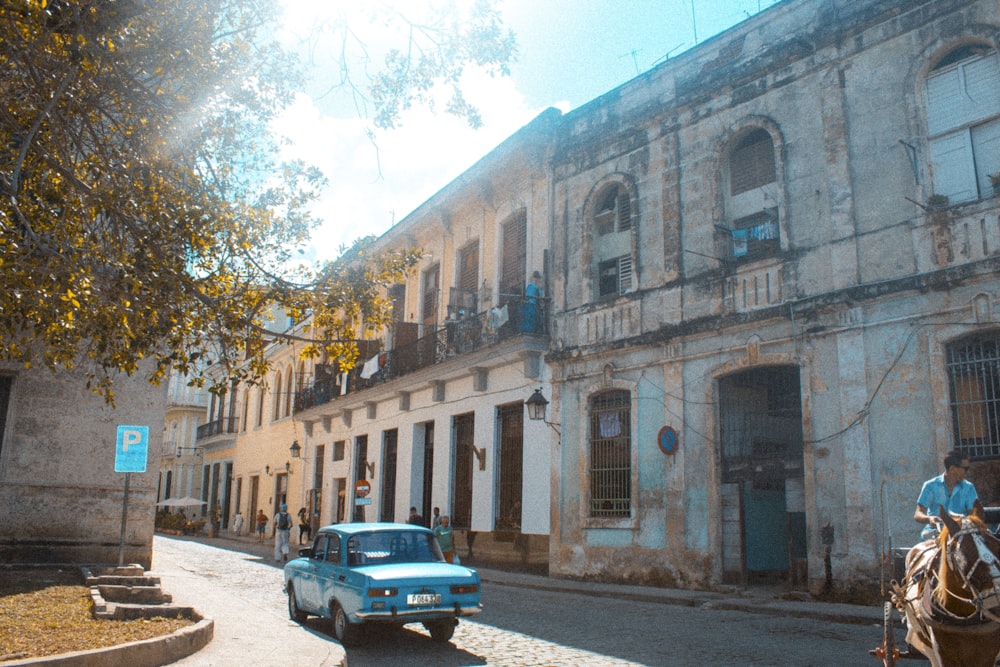 blue sedan passing on road beside building