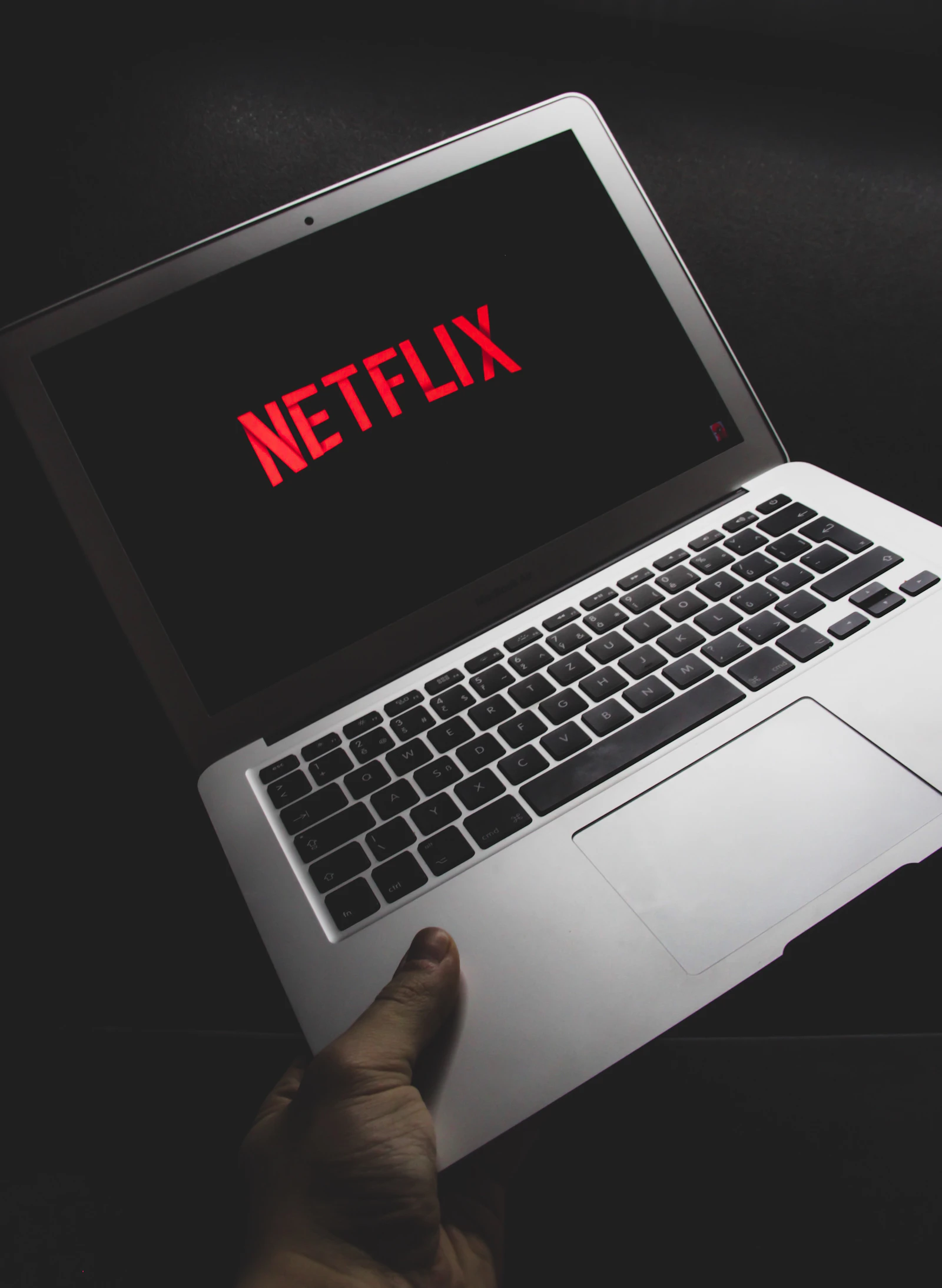 灰色筆記型電腦螢幕上顯示 Netflix 首頁，放在木桌上