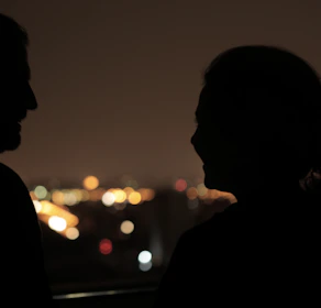 Silhouettes of two people connecting in a softly lit urban setting at night.