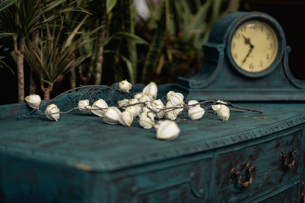 white flowers near black mantel clock