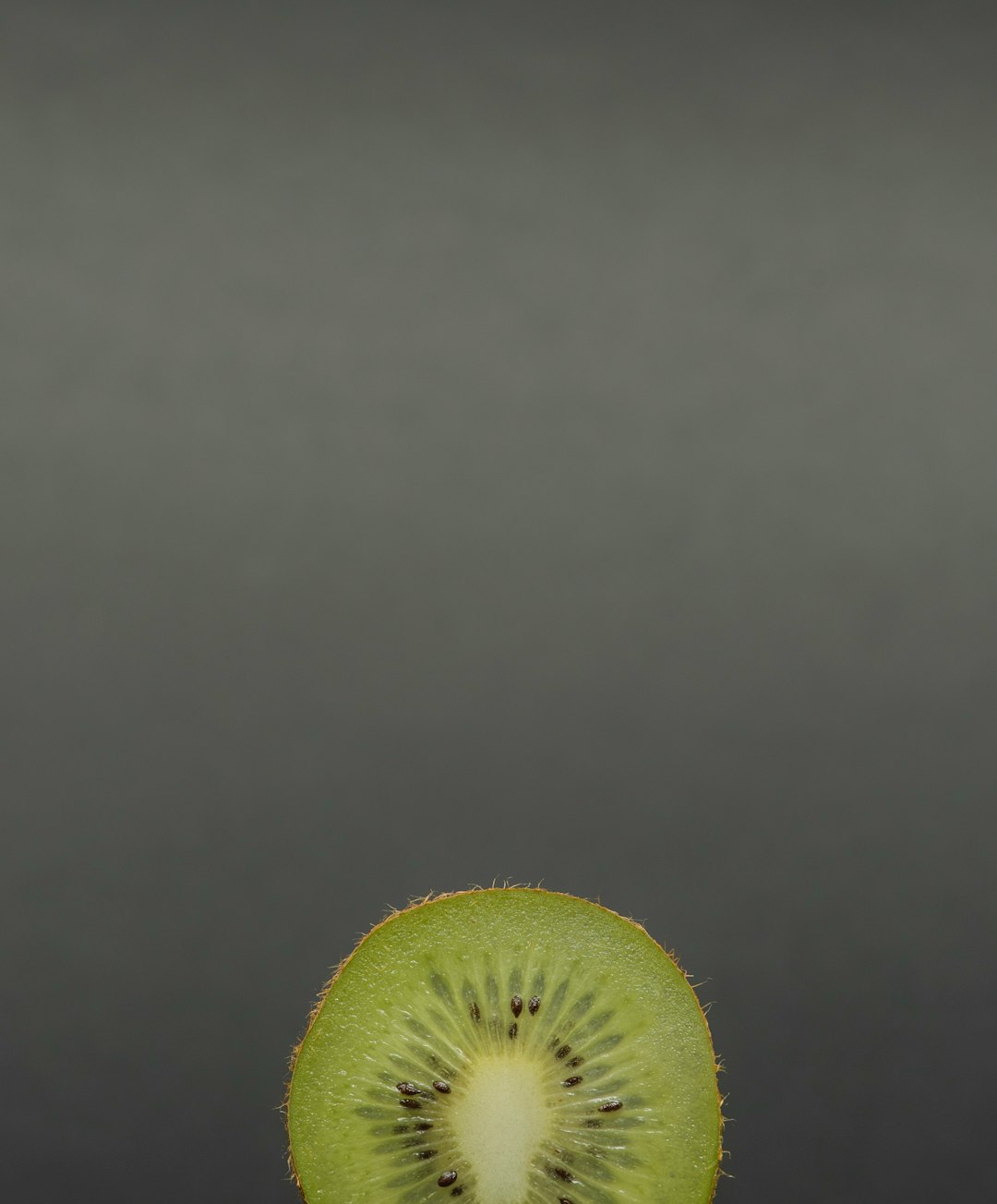 green sliced kiwi fruit on grey panel