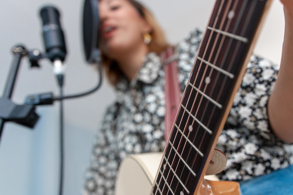 woman playing acoustic guitar while singing using condenser microphone