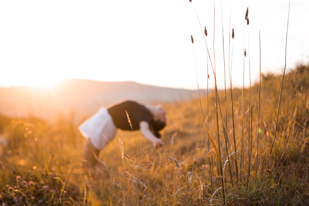 Mujer con camisa negra y falda blanca cayendo sobre su espalda en el campo de hierba