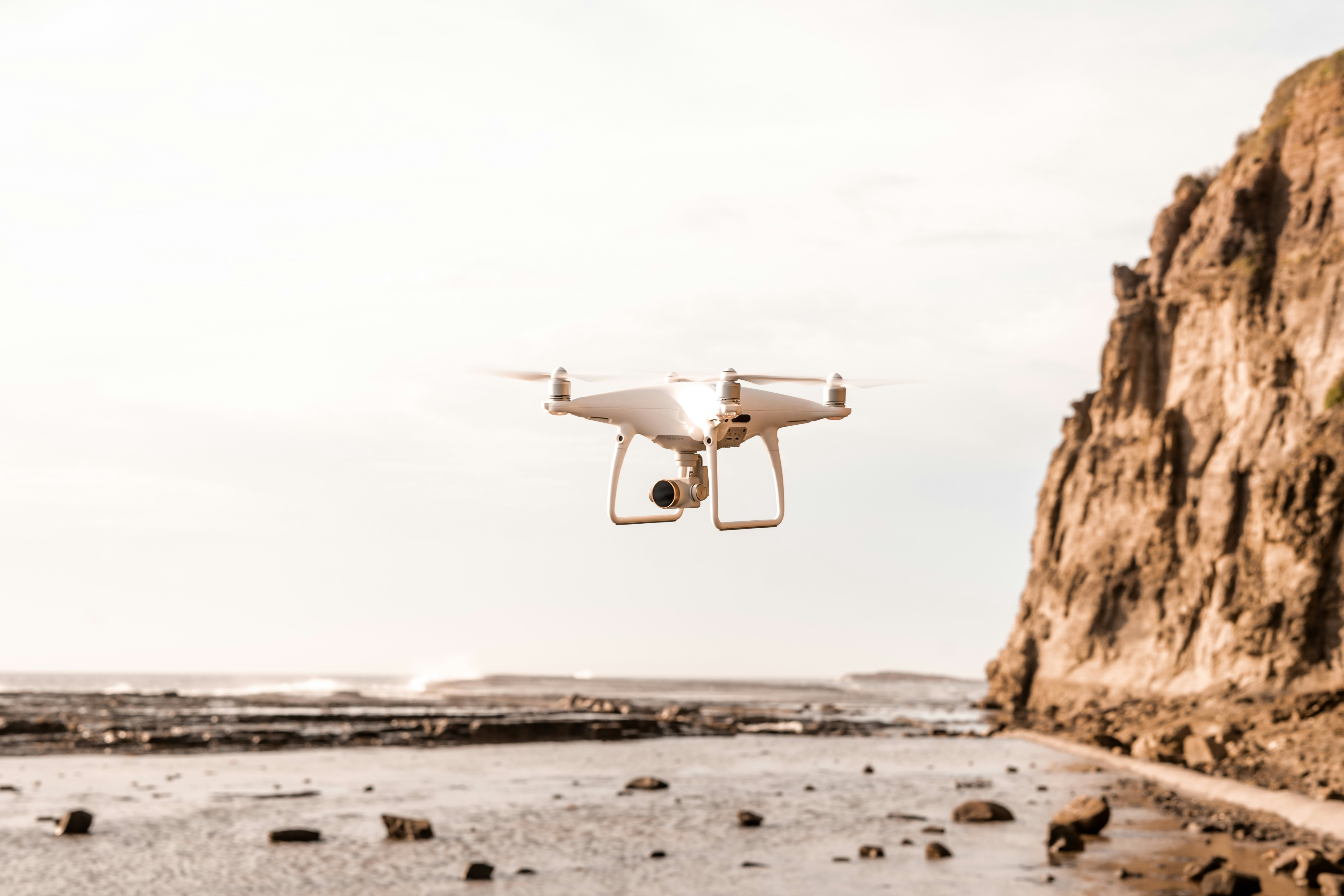 white drone near seashore