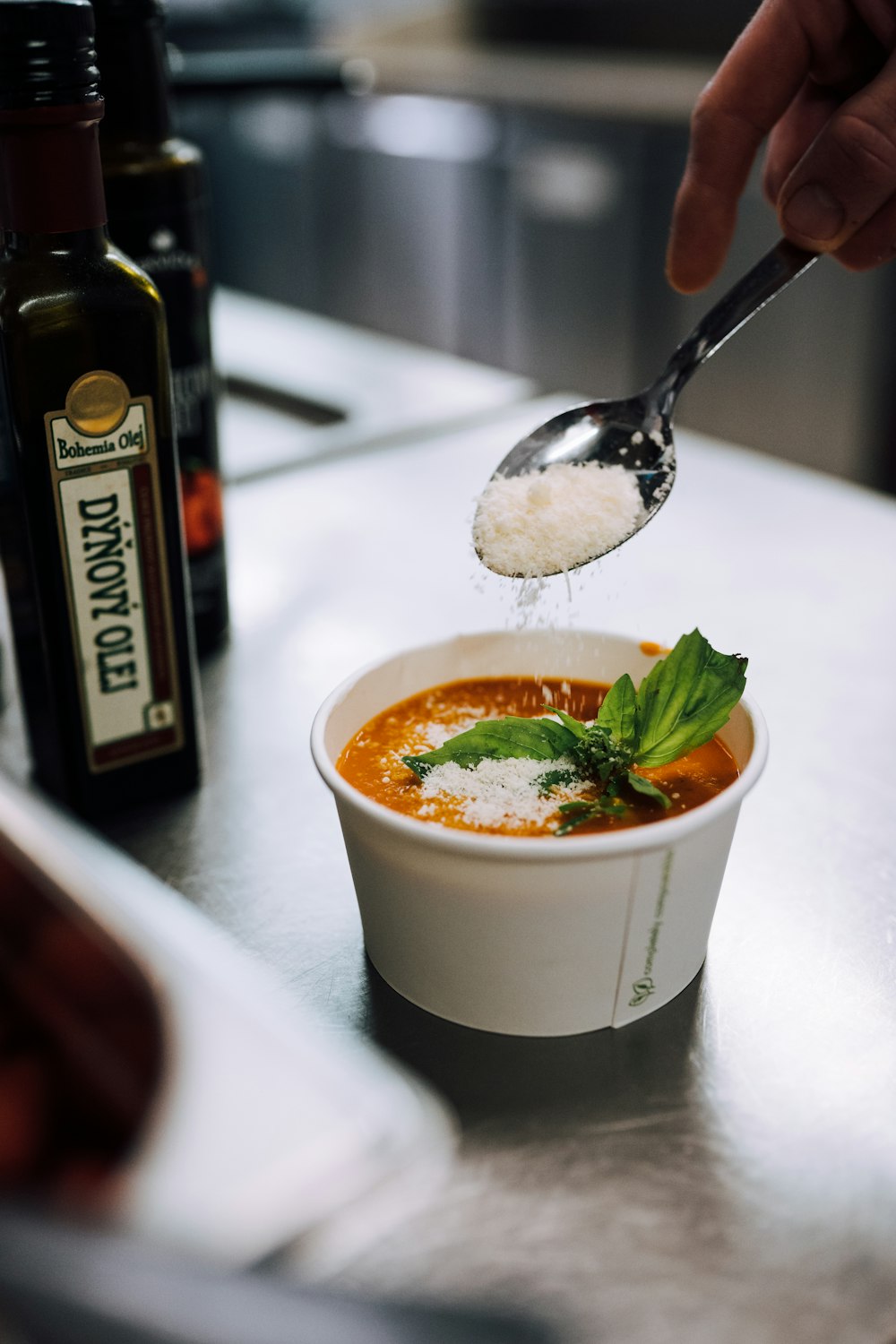 person pouring seasoning on white cup