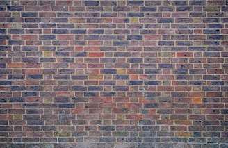 a man sitting on a bench in front of a brick wall