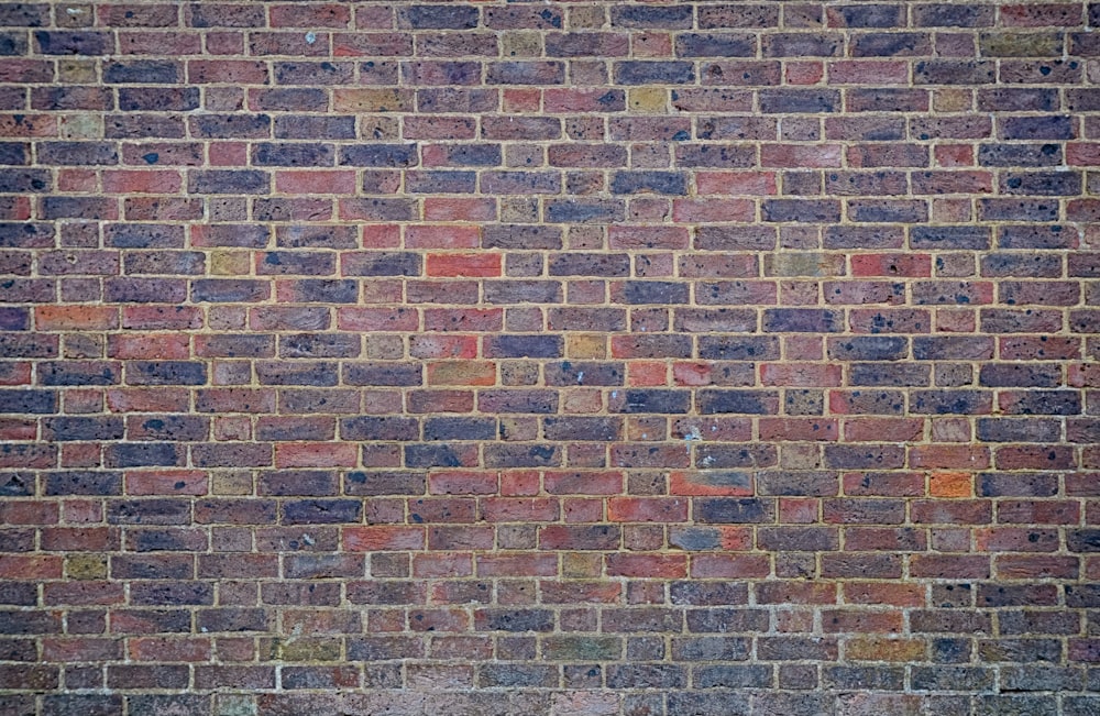 a man sitting on a bench in front of a brick wall