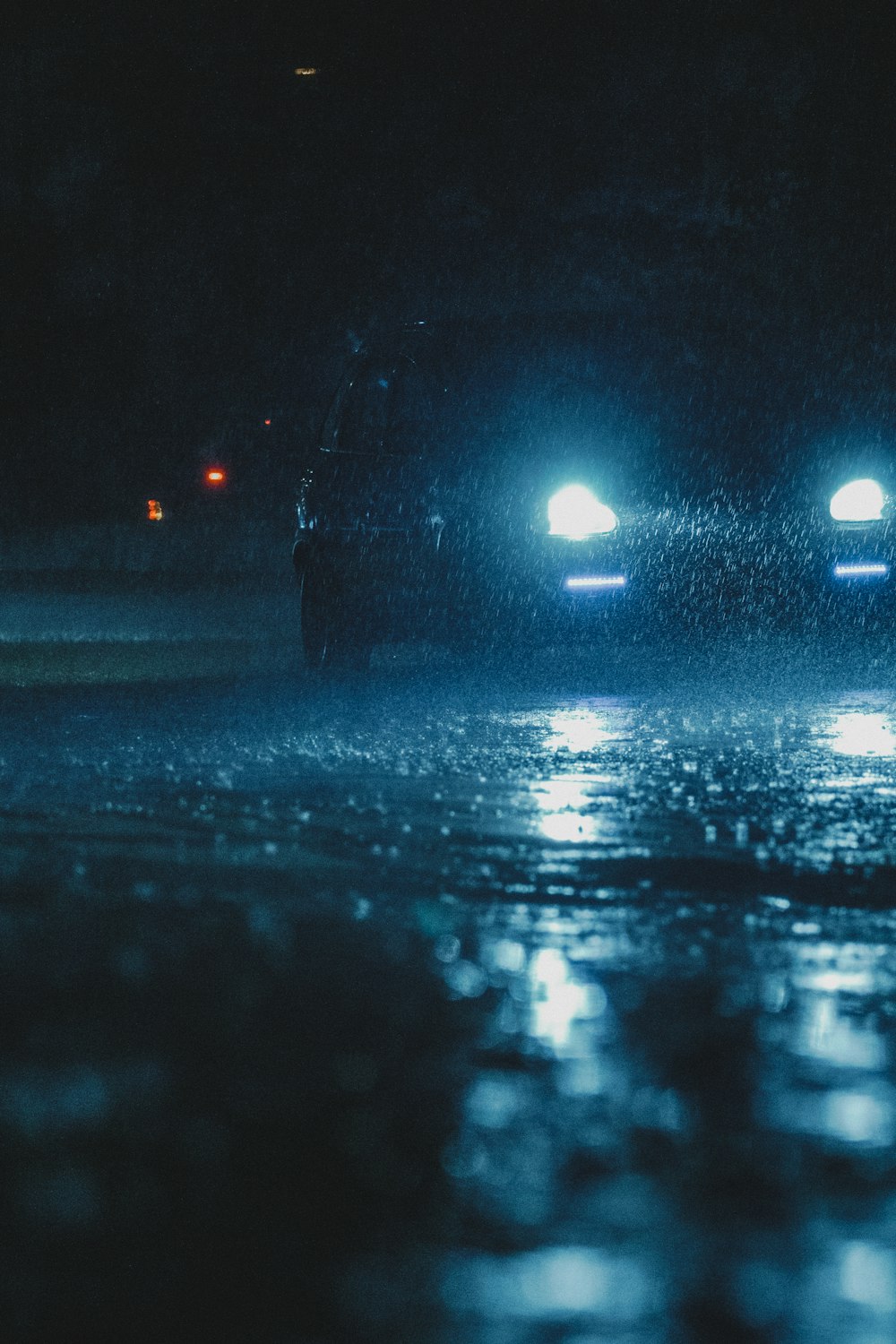 헤드라이트를 켠 차량이 야간에 젖은 도로를 달리고 있습니다.