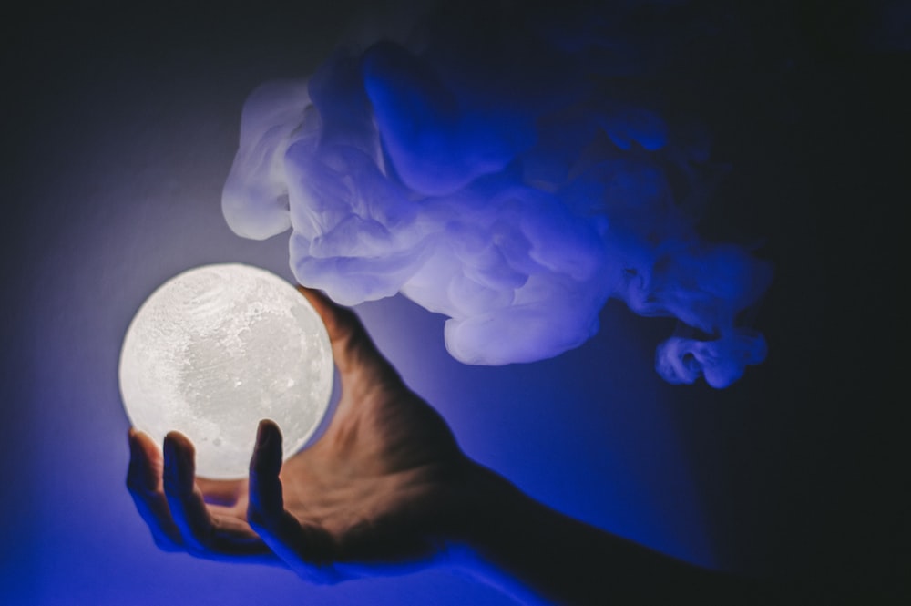 une personne tenant une lune blanche dans sa main