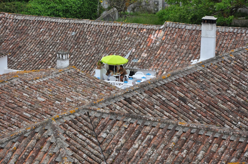 man sitting on chair on rooftop with umbrella during daytime