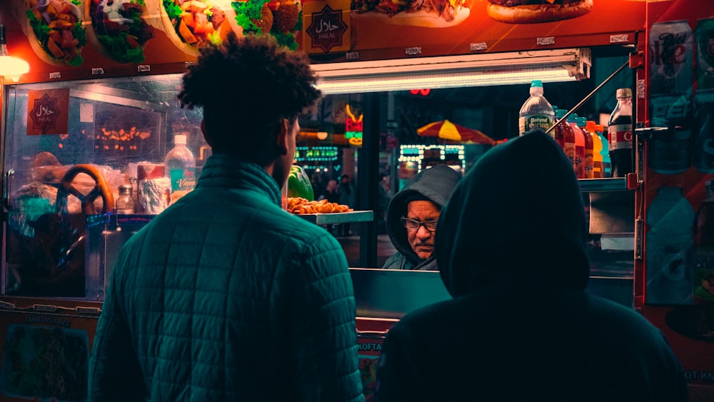 Dos hombres de pie frente a un puesto de comida