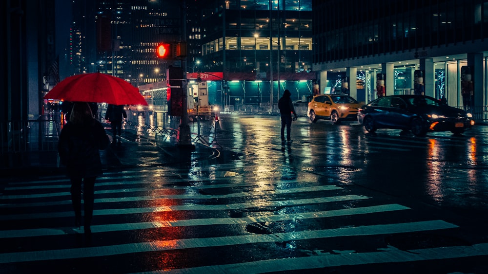 Persona que lleva un paraguas rojo que pasa por el carril peatonal