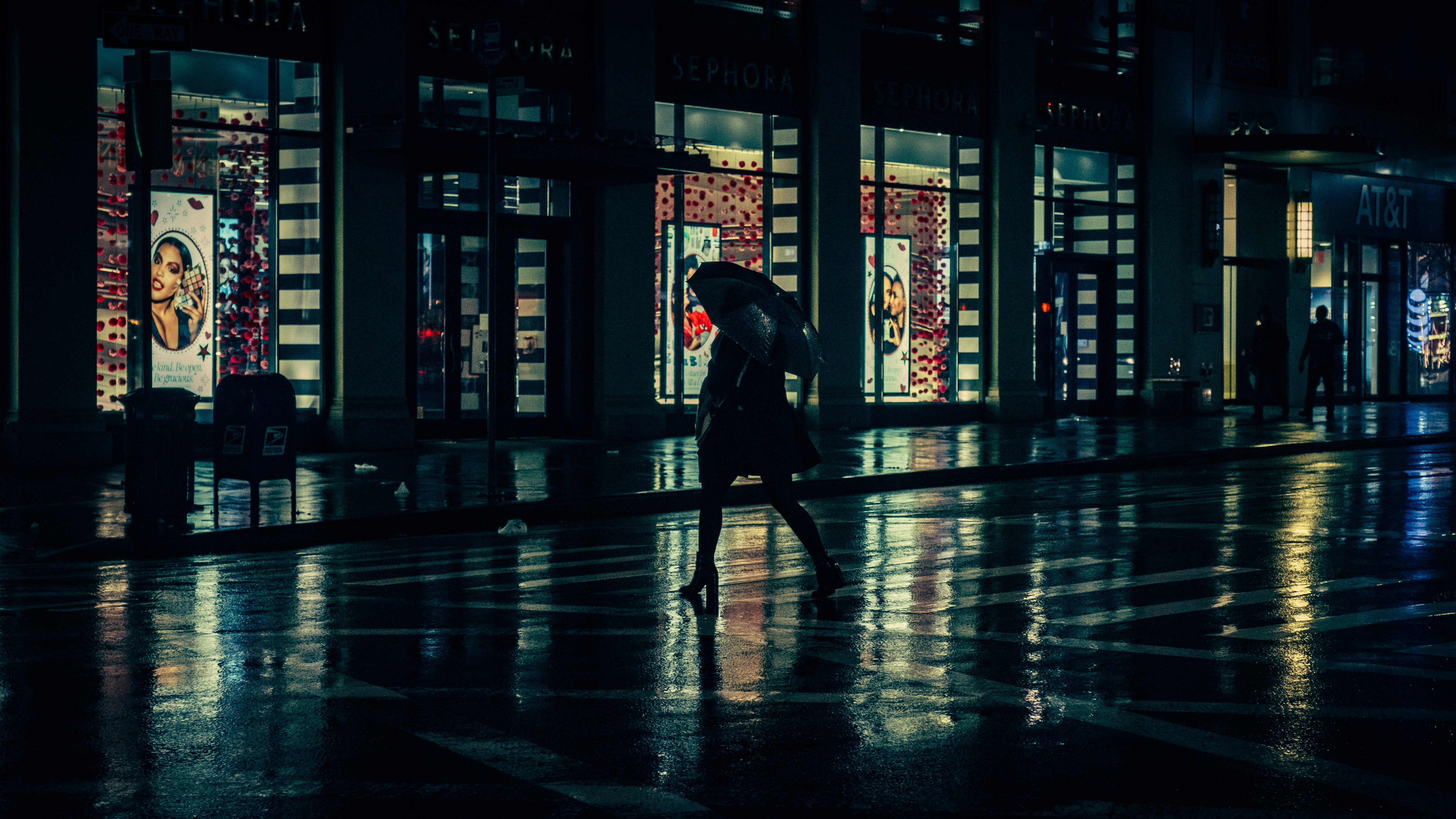person with umbrella walking beside building during nighttime