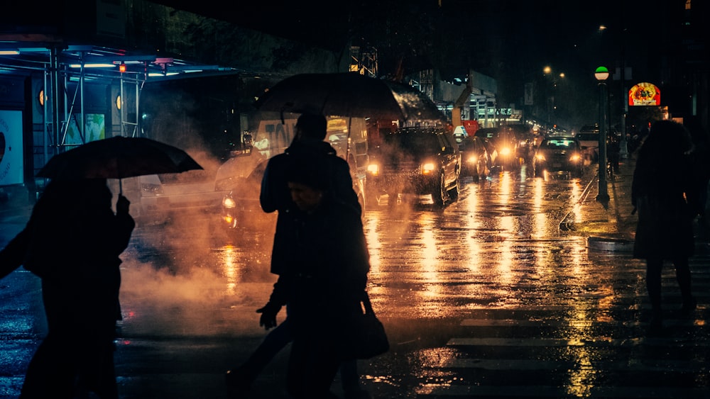 Silhouette von Menschen, die in regnerischer Nacht einen Regenschirm halten