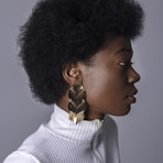 woman wearing white turtleneck top and gold-colored earring