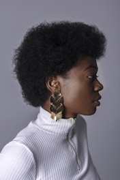 woman wearing white turtleneck top and gold-colored earring