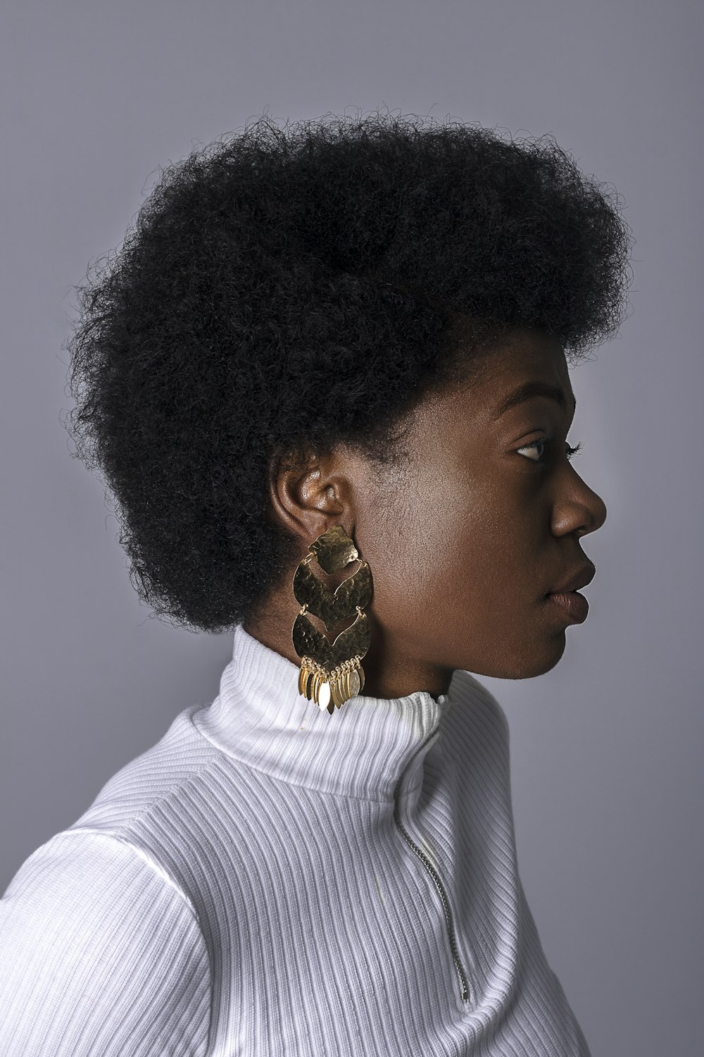 Femme portant un haut à col roulé blanc et une boucle d’oreille dorée