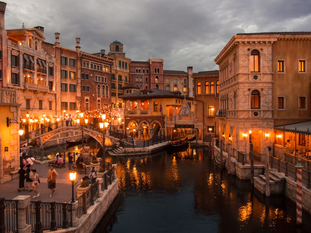 people walking beside river surrounded by buildings