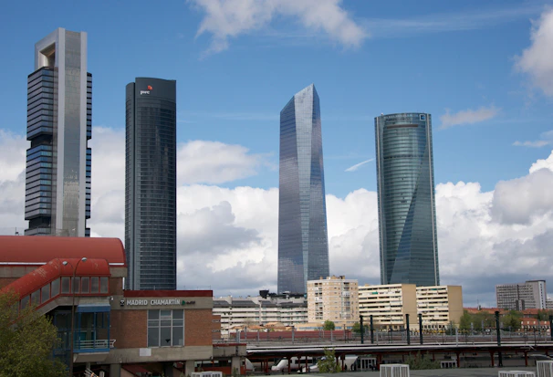 Aerial view of sunny Madrid with white and brown buildings near a calm body of water.