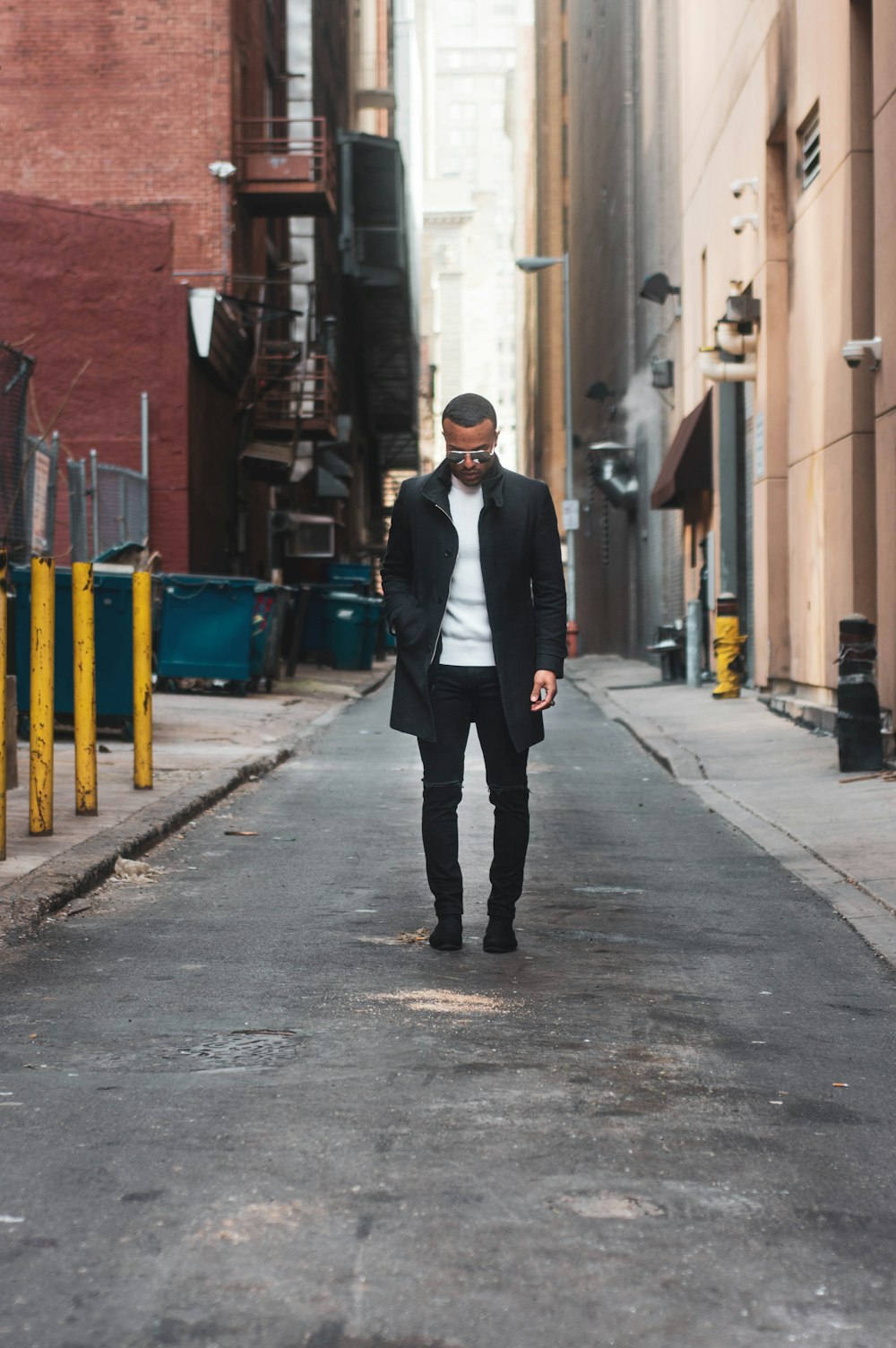 man in gray coat standing on alley
