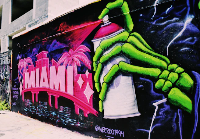 black, green, and pink word Miami spray paint on building wall