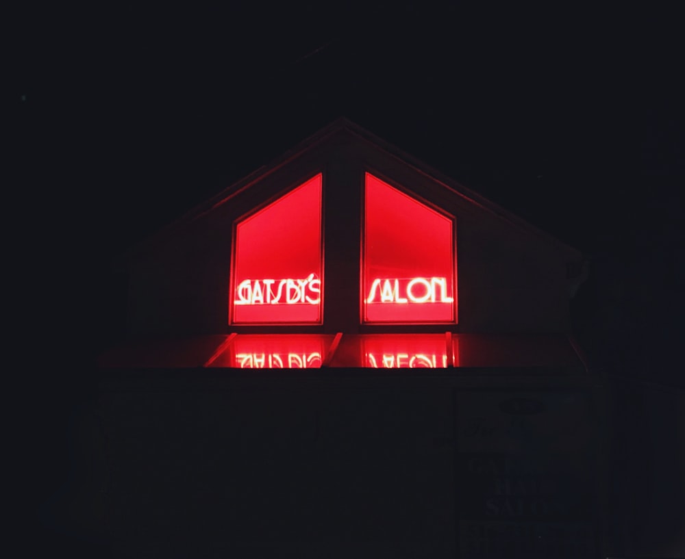 a red neon sign is lit up in the dark