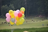 Children laughing and playing with colorful balloons outdoors.