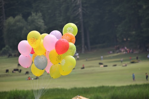 Children laughing and playing with colorful balloons outdoors.