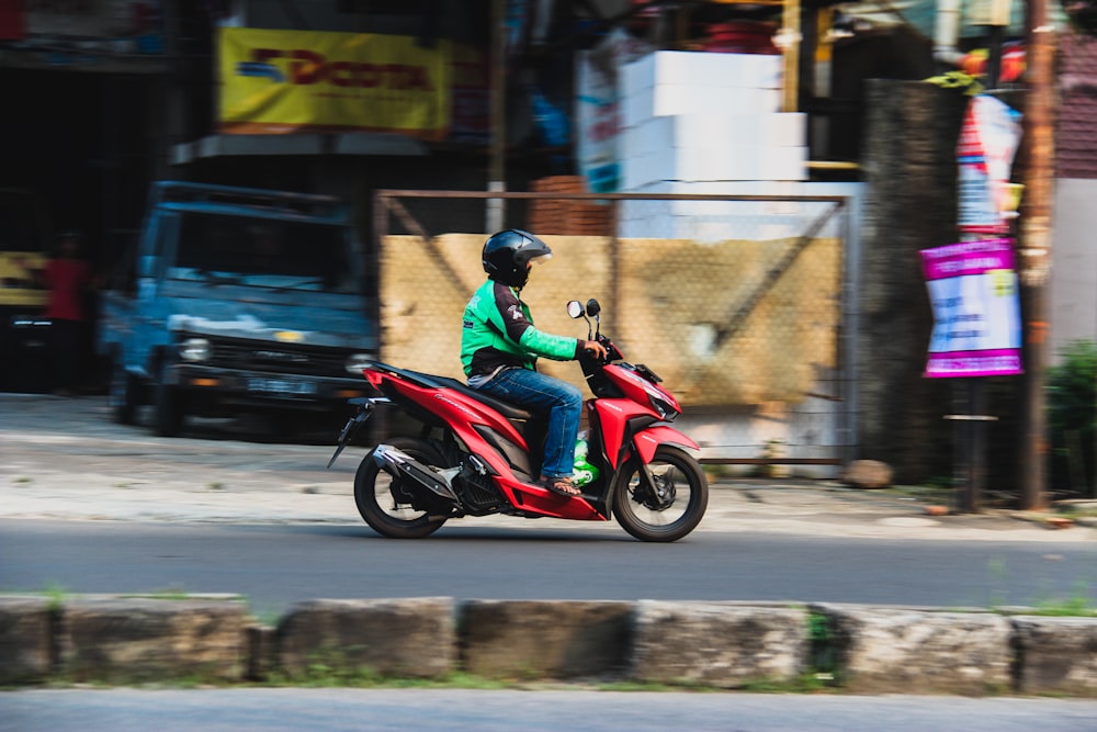 man riding red Honda Vario 150 on road