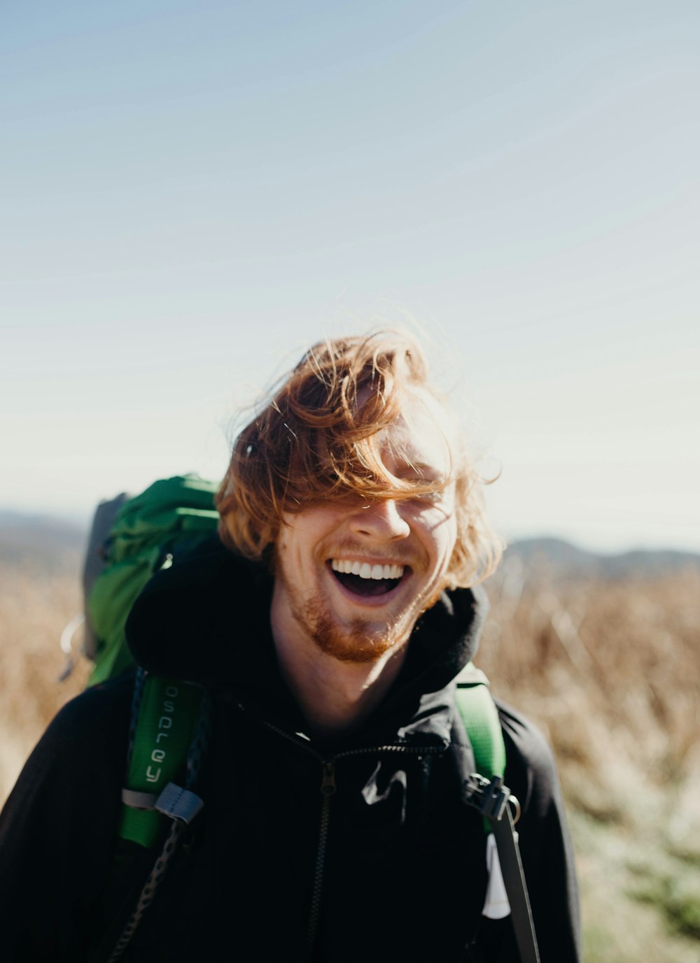 Uomo sorridente con borsa alpinistica verde durante il giorno