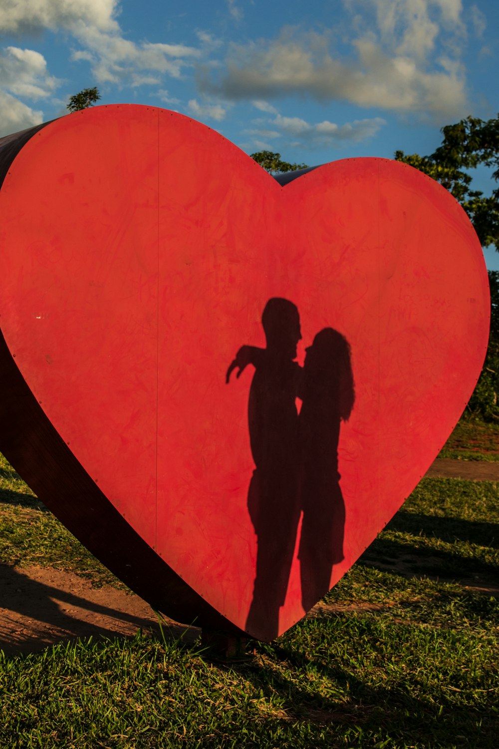 shadow of coupe hugging near red heart statue