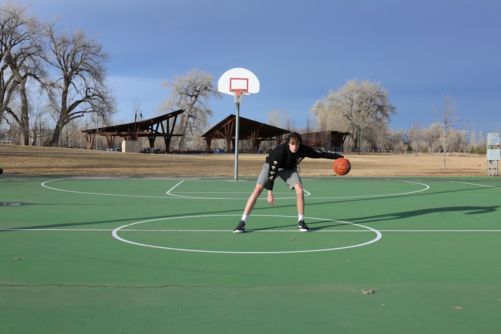 person playing basketball on basketball court during daytime