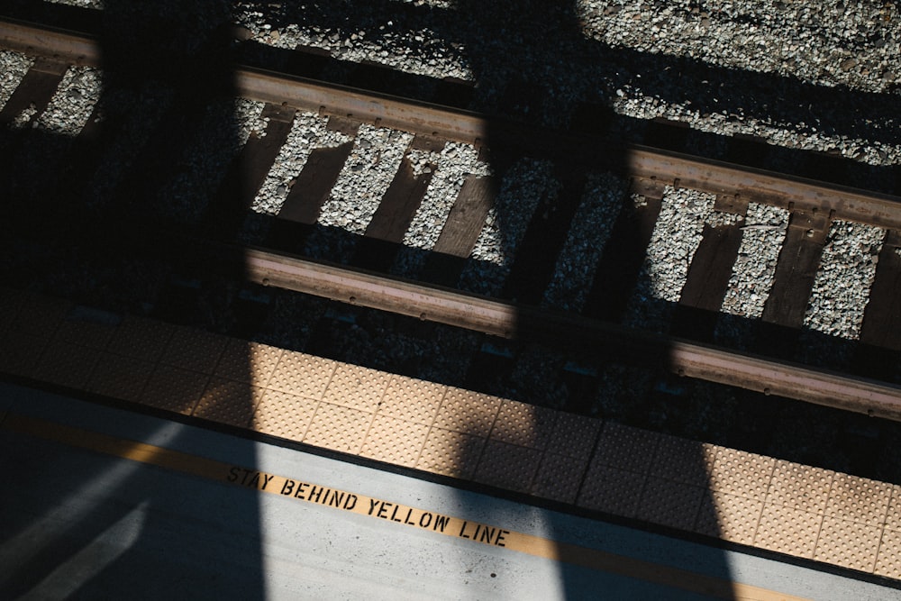 the shadow of a person standing on a train platform