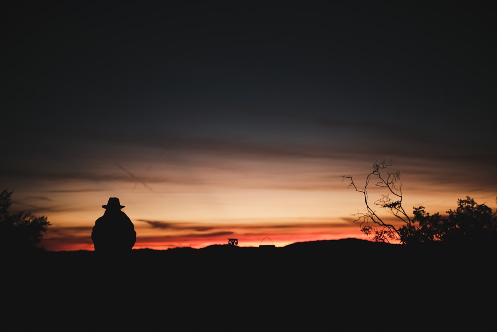 silhouette photography of person sitting on mountain