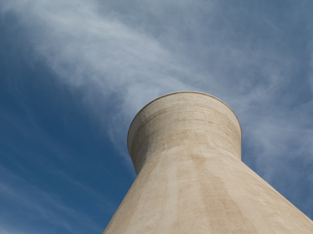 brown factory exhaust tower under blue and white sky during daytime