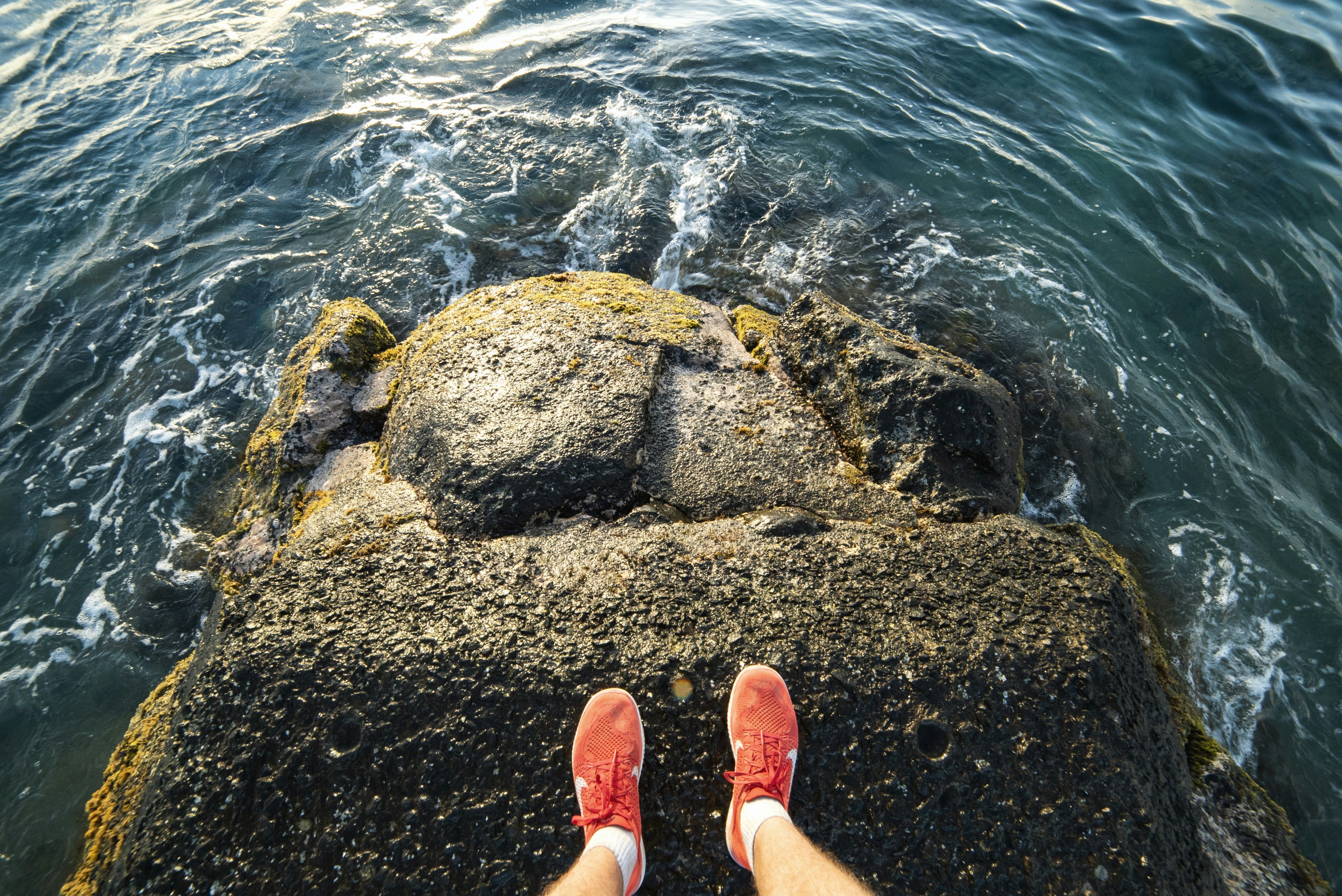 a person standing on top of a rock near the ocean