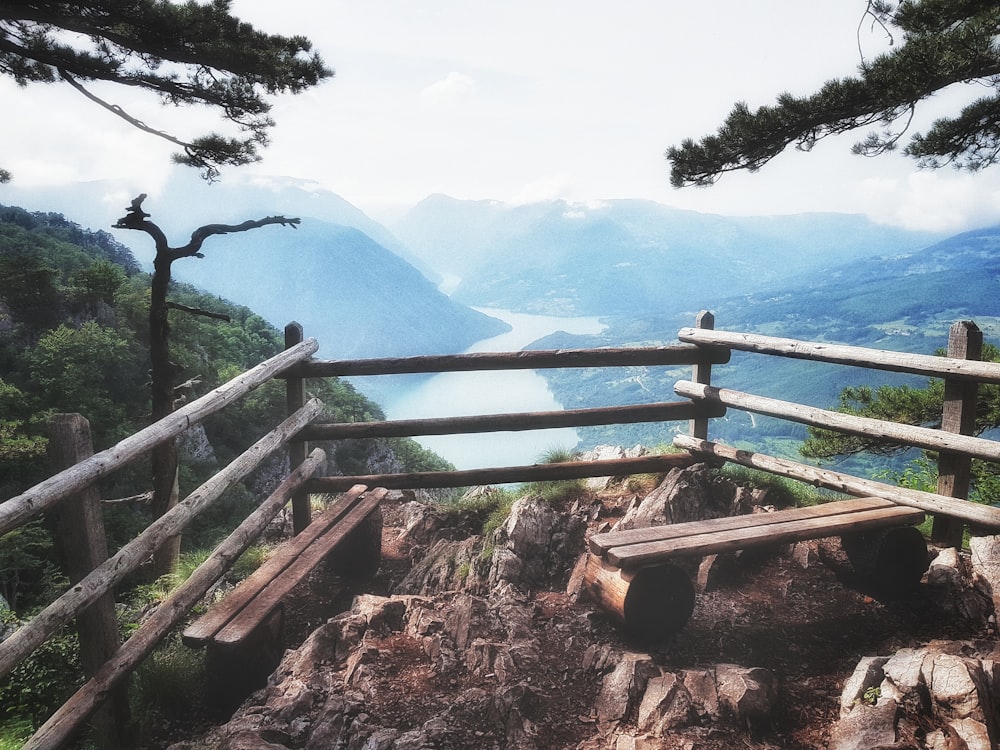 brown wooden bench on top of mountain near river
