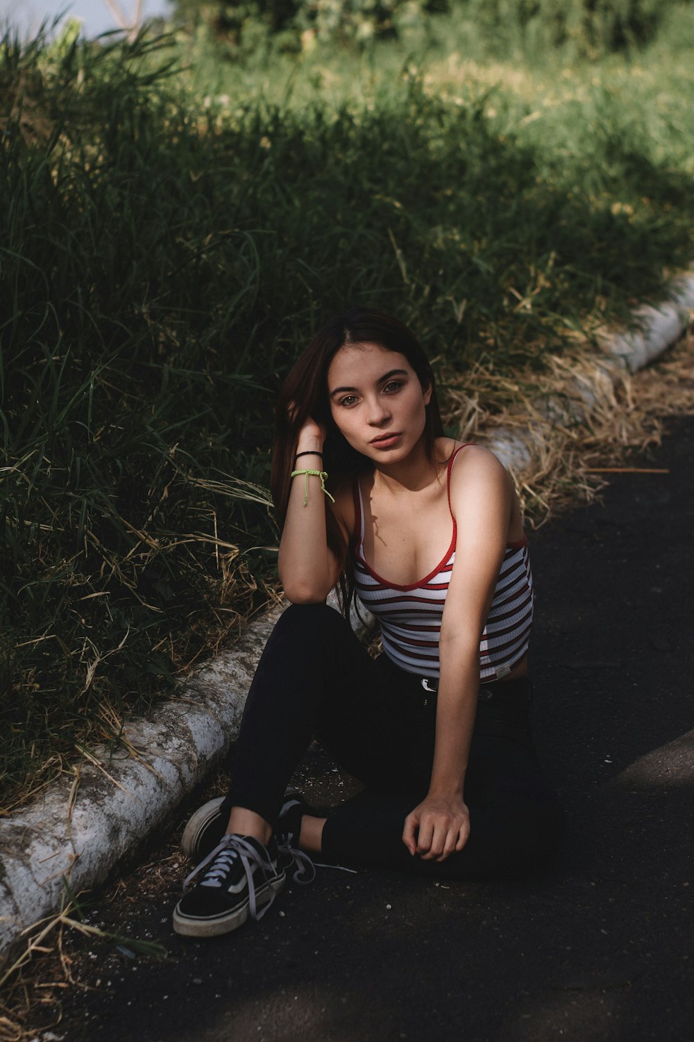 woman sitting on road beside grass