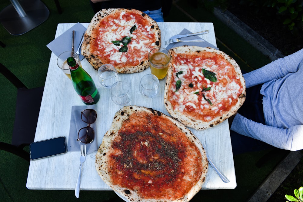 pizza, wine bottle, drinking glasses on table