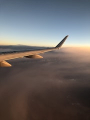 Aerial view of a private jet soaring above the clouds at sunset.