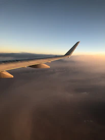 A scenic view of an airplane soaring above fluffy clouds at sunset.