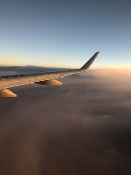 Aerial view of a private jet soaring above the clouds at sunset.