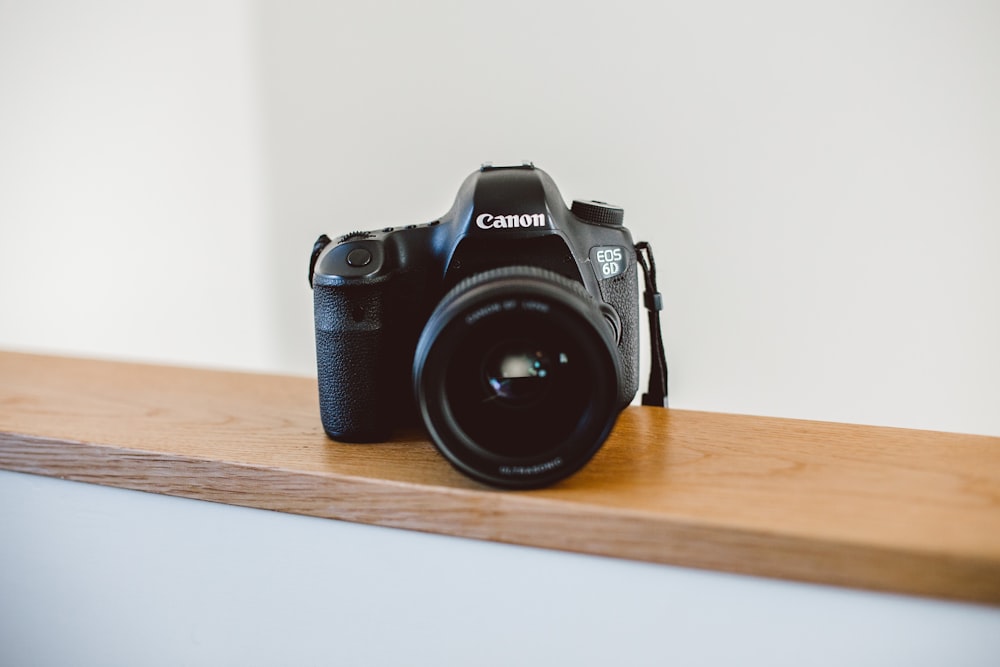 black Canon DSLR camera on brown wooden slab