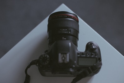 A sleek professional DSLR camera resting on a wooden table with soft studio lighting